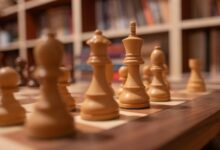 Close-up of wooden chess pieces on a chessboard in a warm, cozy library setting.