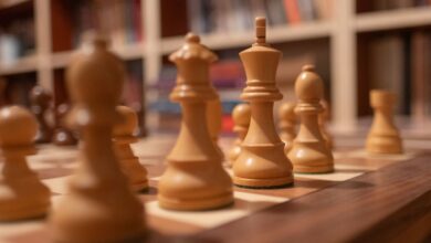 Close-up of wooden chess pieces on a chessboard in a warm, cozy library setting.