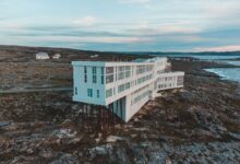 Aerial view of Fogo Island Inn on a rocky coast with ocean backdrop at dusk, Newfoundland.
