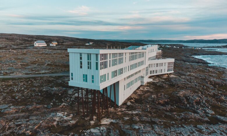 Aerial view of Fogo Island Inn on a rocky coast with ocean backdrop at dusk, Newfoundland.
