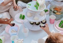 Adults and children enjoying a festive garden party with vibrant cakes and cupcakes.