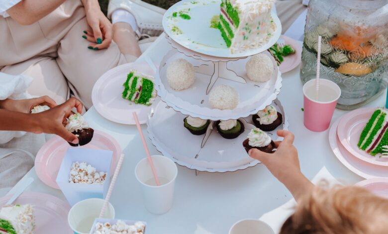 Adults and children enjoying a festive garden party with vibrant cakes and cupcakes.