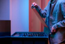 A man carefully fits a glass panel onto a gaming PC while adjusting internal cables.