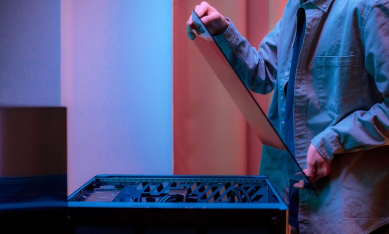 A man carefully fits a glass panel onto a gaming PC while adjusting internal cables.