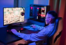 A young man intensely gaming on a computer at home, showcasing a modern gaming setup.