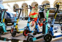 A vibrant collection of electric scooters and bicycles parked on a bustling city street.