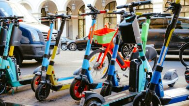 A vibrant collection of electric scooters and bicycles parked on a bustling city street.