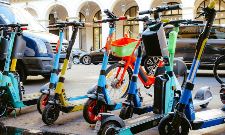 A vibrant collection of electric scooters and bicycles parked on a bustling city street.