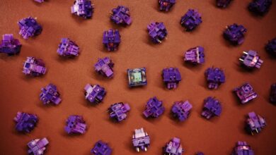 Flat lay of purple mechanical keyboard switches scattered on a brown surface.