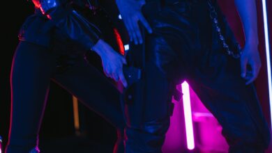 Two people in dark, neon-lit room holding weapons, creating a dramatic scene.