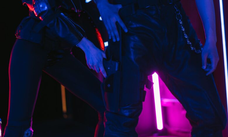 Two people in dark, neon-lit room holding weapons, creating a dramatic scene.
