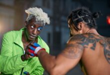 Two martial artists in an intense urban setting, displaying combat skills and tattoos.