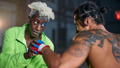 Two martial artists in an intense urban setting, displaying combat skills and tattoos.