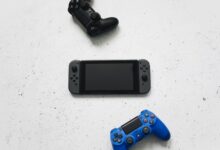 Flat lay of gaming consoles and controllers on white surface, featuring popular gaming devices.