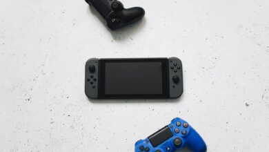 Flat lay of gaming consoles and controllers on white surface, featuring popular gaming devices.