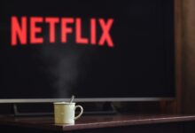 A steaming mug on a table in front of a TV displaying Netflix, creating a cozy indoor atmosphere.