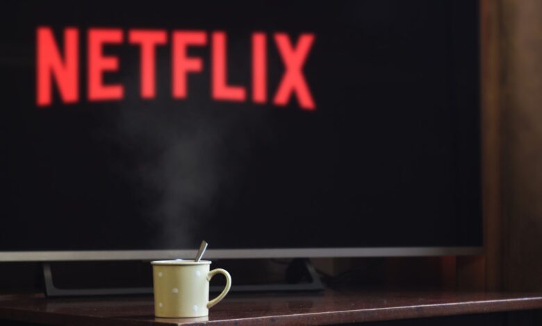 A steaming mug on a table in front of a TV displaying Netflix, creating a cozy indoor atmosphere.