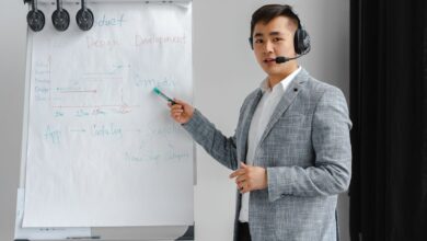 Asian man in a gray suit giving a presentation with a flipchart, wearing a headset.