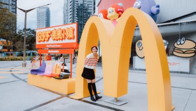 Fashion model poses at McDonald's landmark in vibrant urban setting.