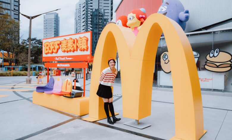 Fashion model poses at McDonald's landmark in vibrant urban setting.