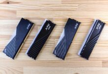Four XPG DDR5 RAM modules aligned on a wooden surface, showcasing modern computing technology.
