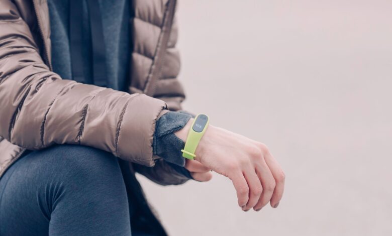 A person wearing a green fitness tracker and winter clothing outdoors. Perfect for health and lifestyle themes.