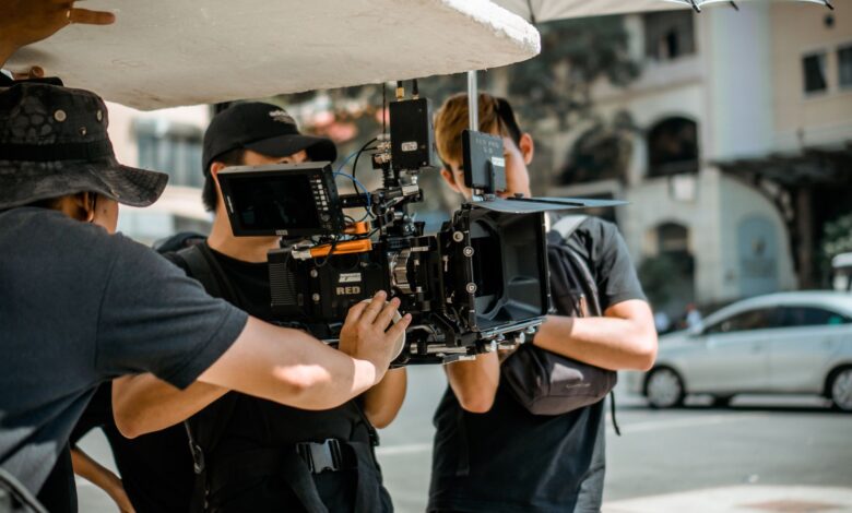 A film crew operates a RED camera on a city street, capturing a professional scene.