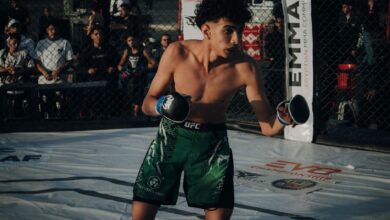 Young male fighter in action during an MMA fight in a cage.