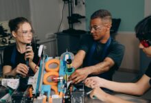 Three engineers collaborate on industrial machinery, emphasizing teamwork and technology in a manufacturing setting.