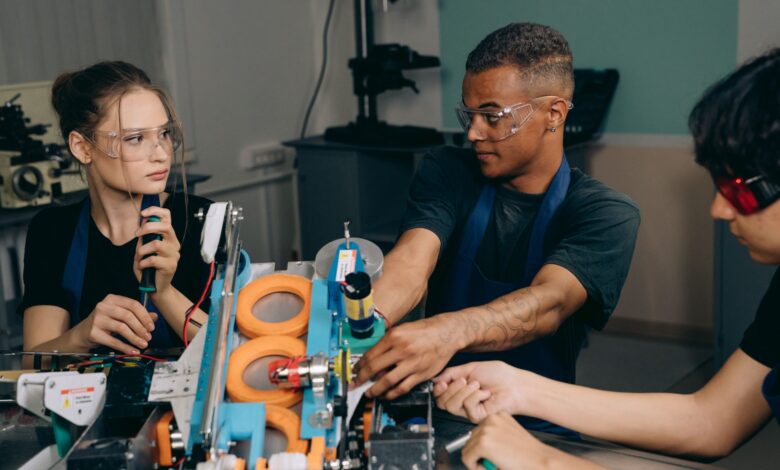 Three engineers collaborate on industrial machinery, emphasizing teamwork and technology in a manufacturing setting.