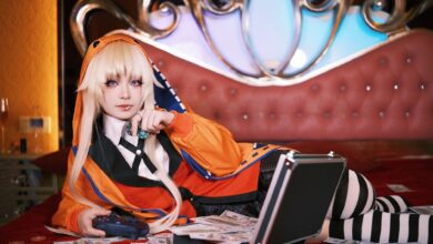 Cosplayer in vibrant outfit lounging on bed with game controller and cash, creating a playful scene.