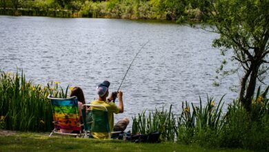 A couple enjoys a peaceful fishing day by a serene lake during summer.