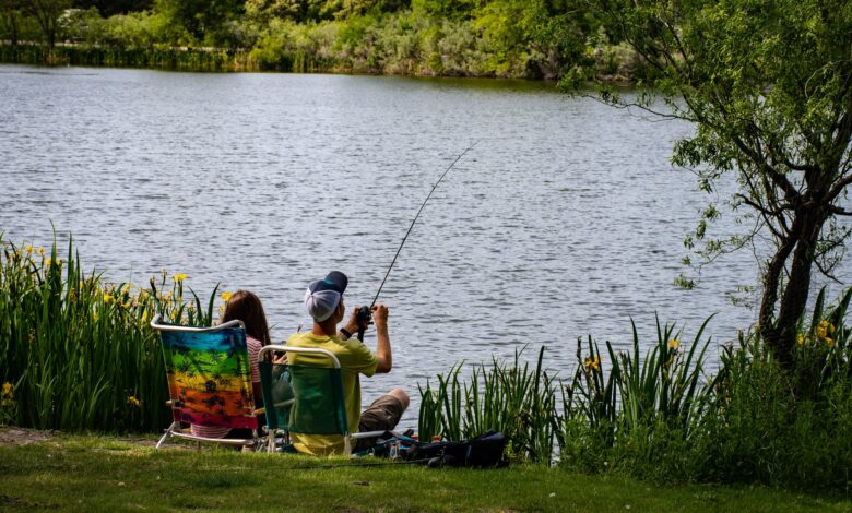 A couple enjoys a peaceful fishing day by a serene lake during summer.