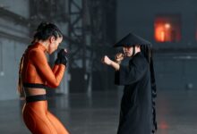Cosplayers engage in a dramatic martial arts pose, inspired by game characters, indoors.
