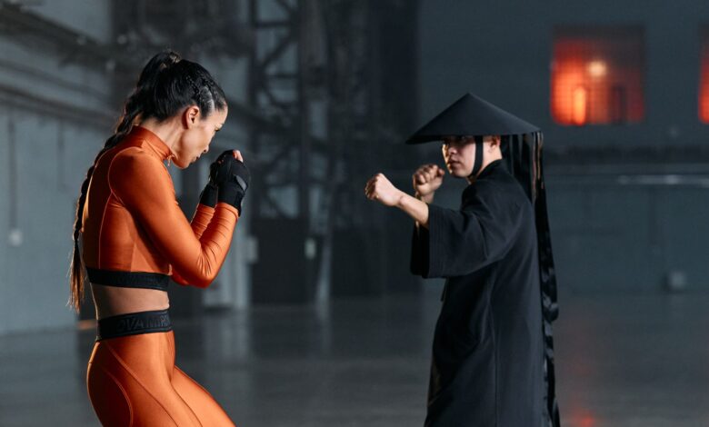 Cosplayers engage in a dramatic martial arts pose, inspired by game characters, indoors.