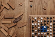Flat lay of a strategy board game with wooden pieces and a game board on a wooden table.
