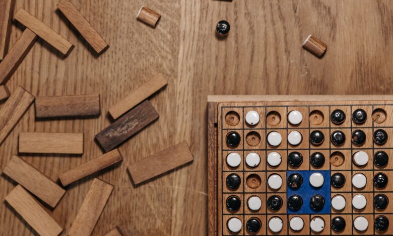 Flat lay of a strategy board game with wooden pieces and a game board on a wooden table.