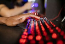 Close-up of a hand on a vibrant RGB-lit gaming keyboard during gameplay.