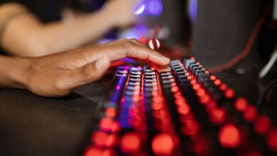 Close-up of a hand on a vibrant RGB-lit gaming keyboard during gameplay.