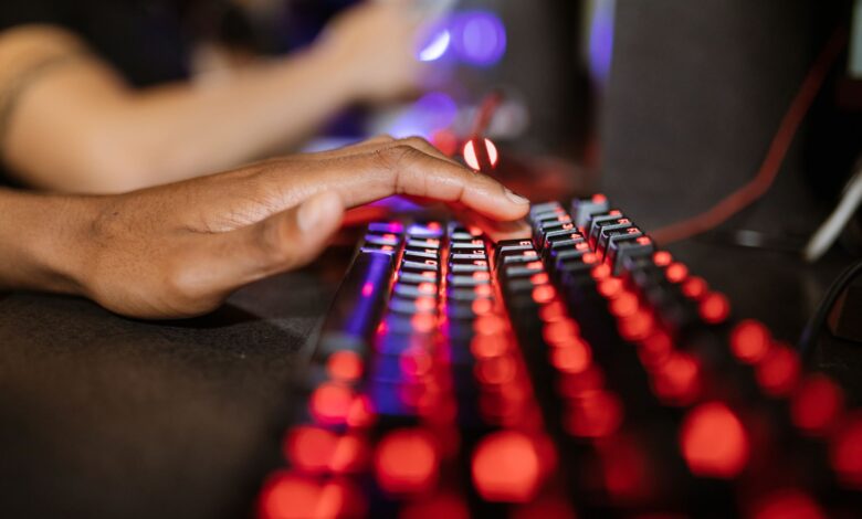 Close-up of a hand on a vibrant RGB-lit gaming keyboard during gameplay.