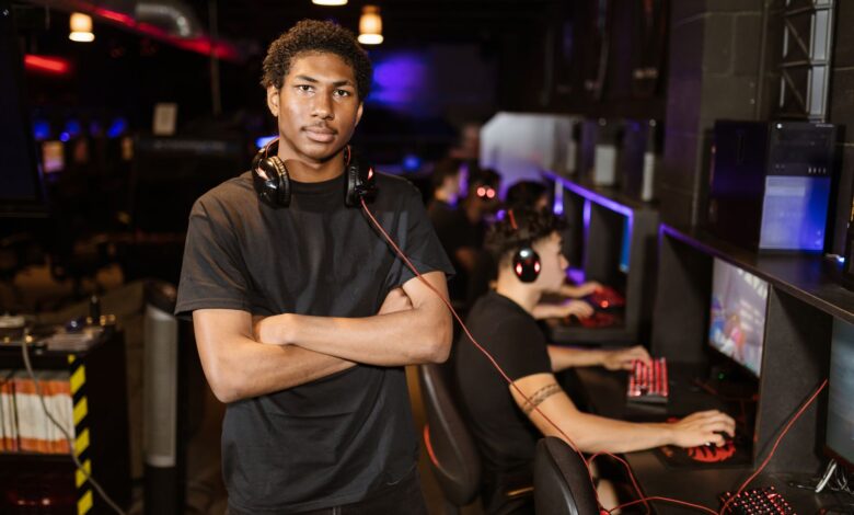 Young gamer standing with arms crossed in an esports arena, exuding confidence.