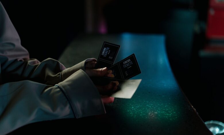 Moody image of a person holding cinema tickets at night, highlighting anticipation of a movie night.