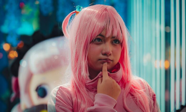 Close-up of young woman in pink wig and costume, pondering indoors.