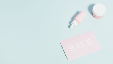Pink beauty products and sale sign on pastel backdrop.