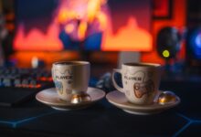 Two gaming-themed espresso cups with chocolates on a colorful gaming setup background.