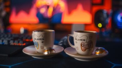 Two gaming-themed espresso cups with chocolates on a colorful gaming setup background.