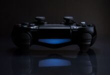 Close-up of a gaming controller with a soft blue light in a dark setting.