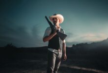 Dramatic portrait of a cowboy with shotgun in San Antonio at nightfall.