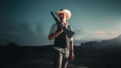 Dramatic portrait of a cowboy with shotgun in San Antonio at nightfall.