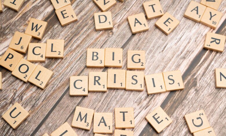 Wooden tiles forming the words 'Big Crisis' on a wooden background.